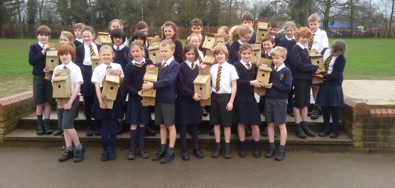 Photo of school children holding bird boxes they have built